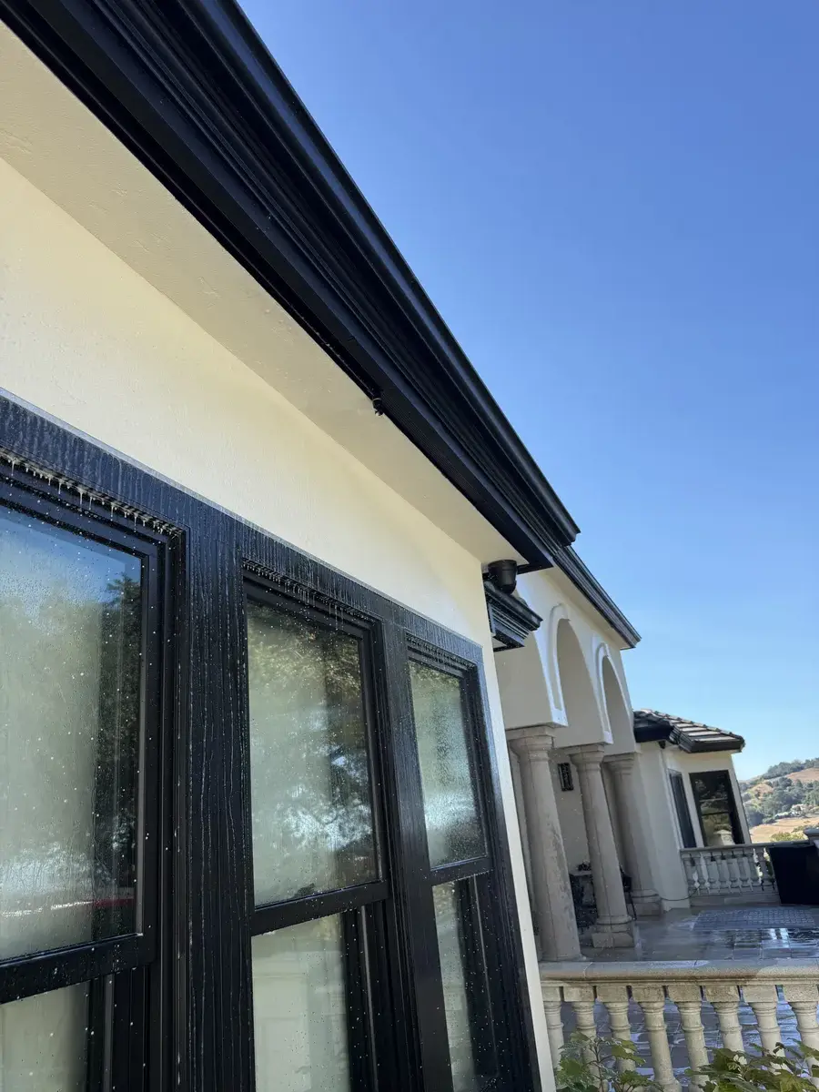 Eave-mounted sprinkler nozzles protecting soffits and window frames from ember intrusion