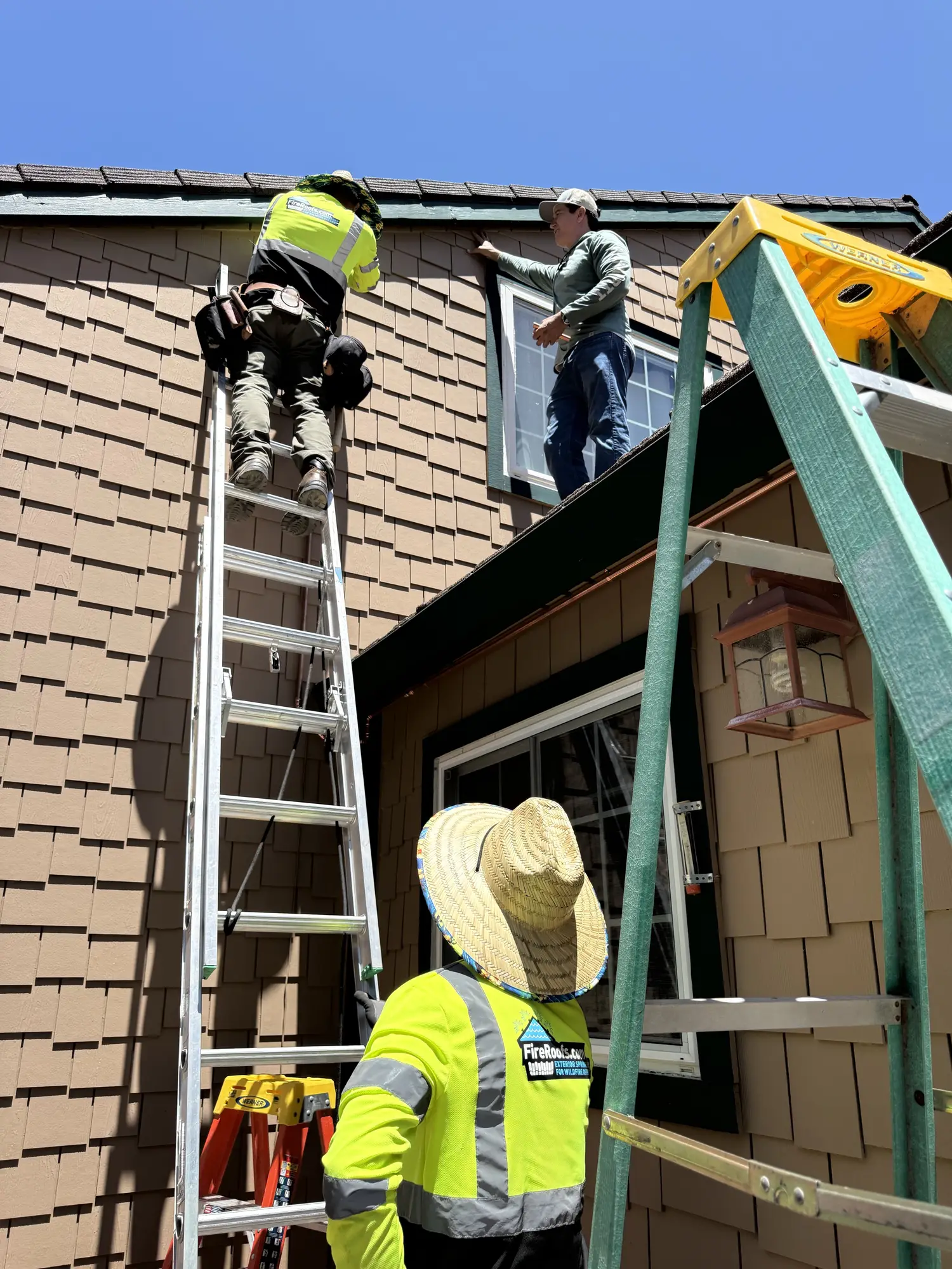 FireRoofs crew installing exterior wildfire protection on a Bay Area home, working from ladders along the roofline and eaves