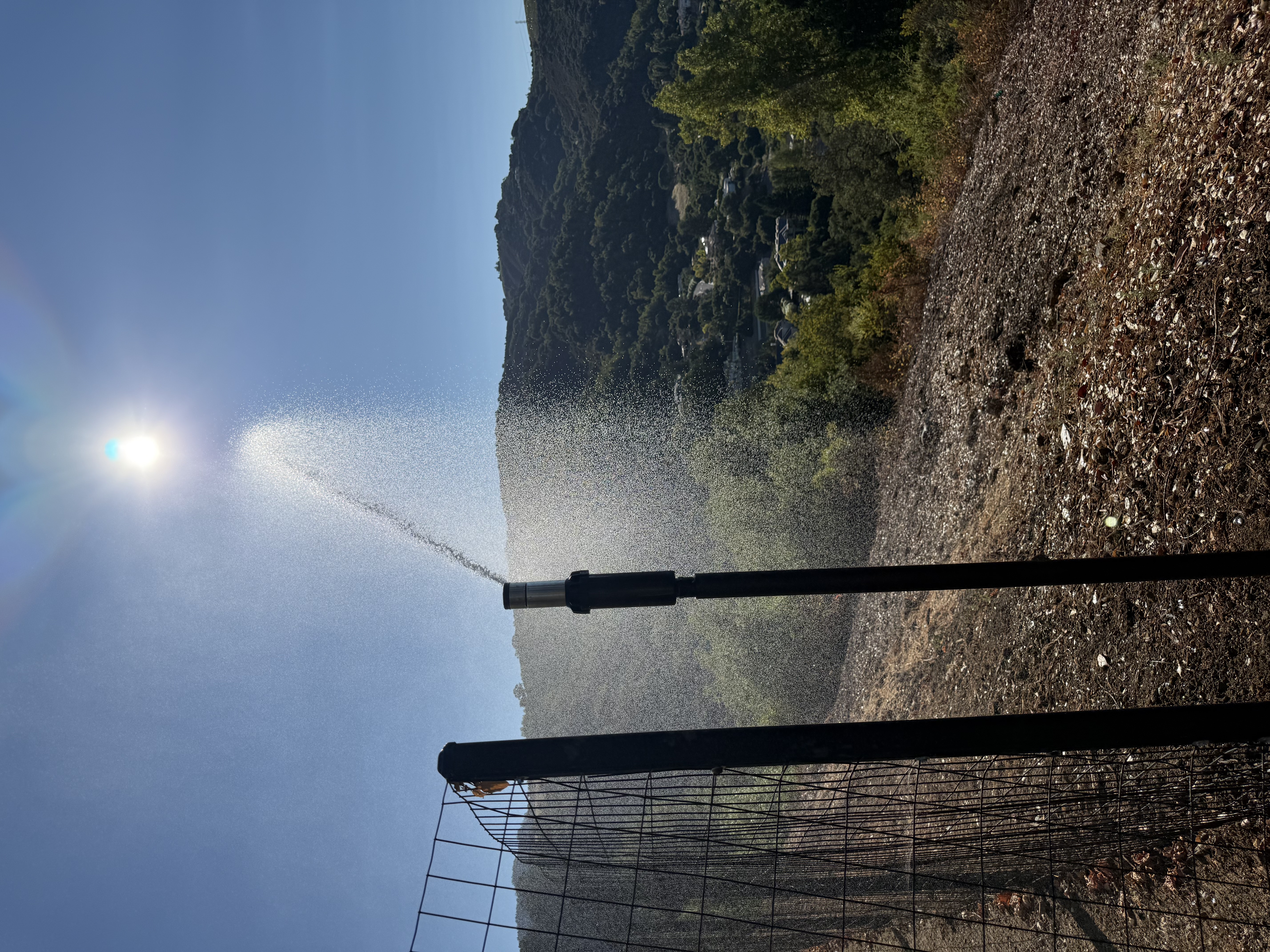 FireRoofs perimeter ground sprinkler spraying water across hillside vegetation