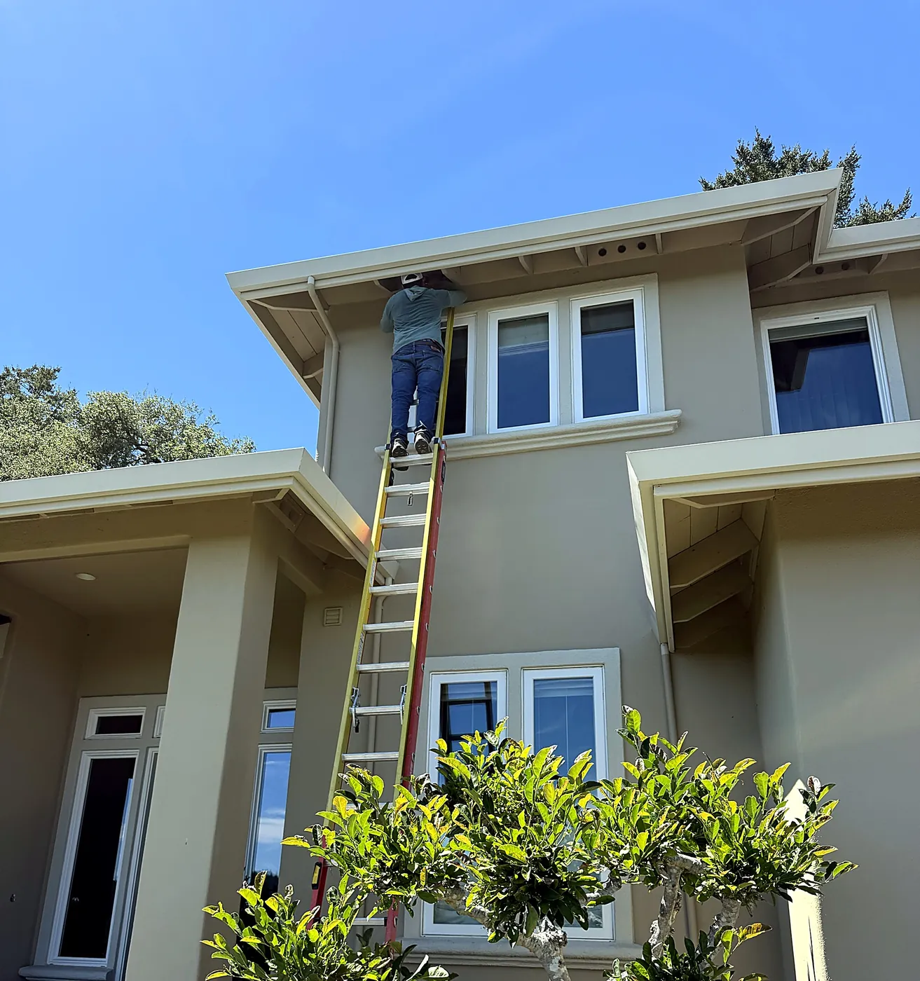 FireRoofs installer on a ladder fitting ember-resistant eave vent screens on a Scotts Valley home